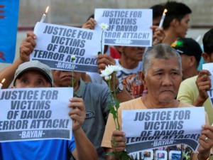 Rallyists display placards condemning the bombing at a market in Davao city during a candlelight protest in front of the Catholic church in Quiapo city, metro Manila. Photo: Reuters